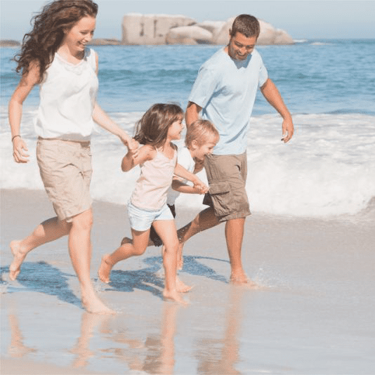 Niños corriendo en la playa con sus padres