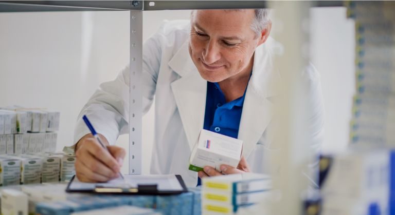 Médico llenando formularios con medicamento en mano