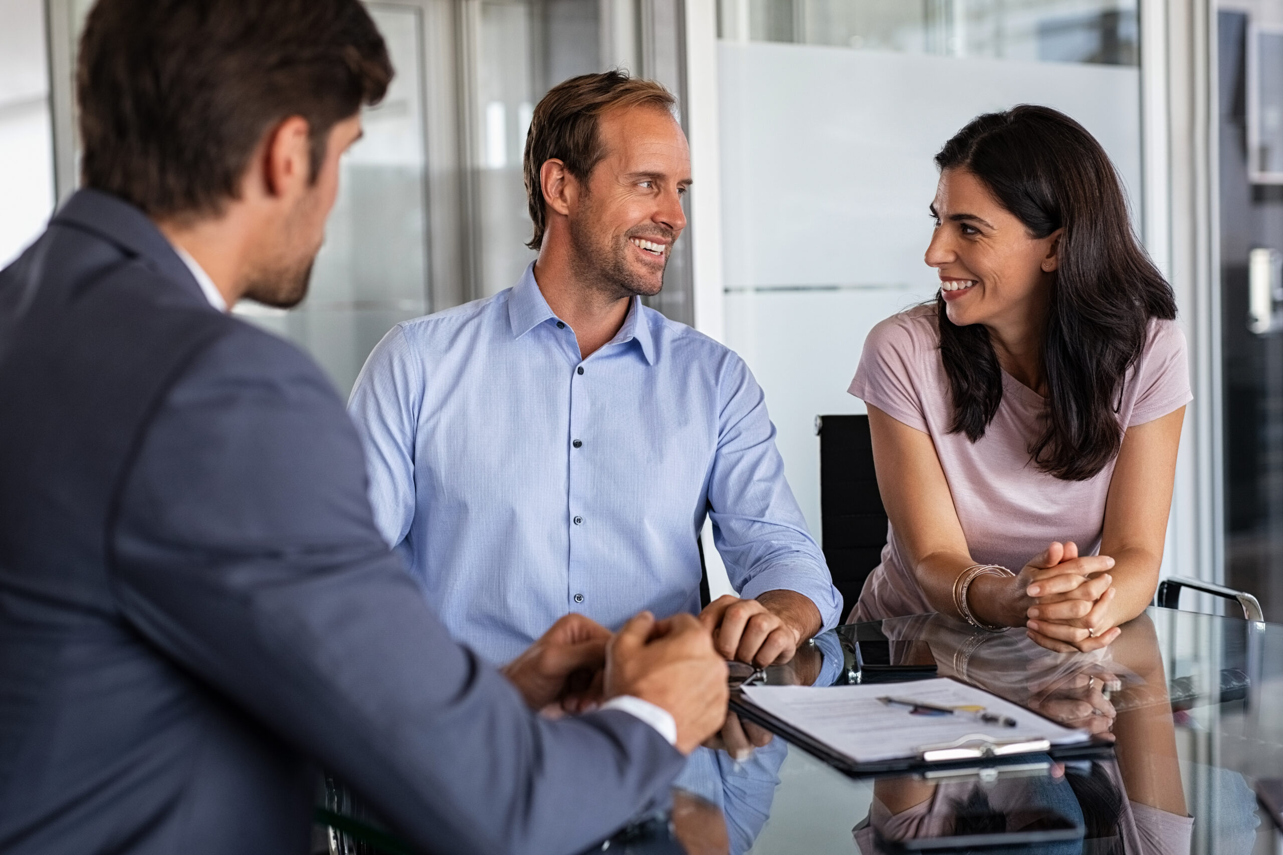 Mature smiling couple meeting financial advisor for investment at office. Financial consultant presents bank investments to man and happy woman. Middle aged couple consulting their bank agent. Saving